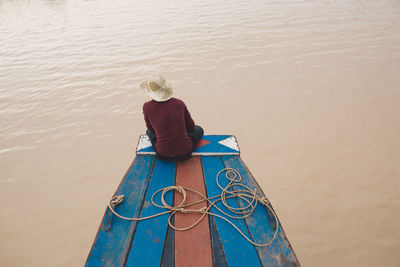 Rear view of woman sitting on boat over sea