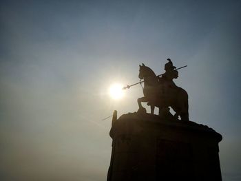 Low angle view of silhouette statue against sky