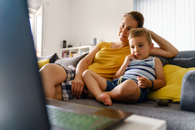 Father and son sitting on sofa at home