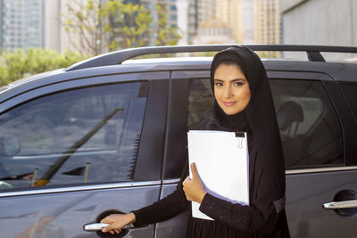 Portrait of woman in burka standing by car