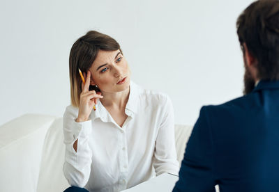 Businesswoman using mobile phone while standing against white background