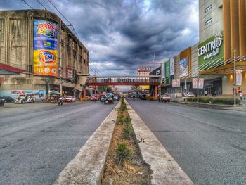 View of city street against cloudy sky