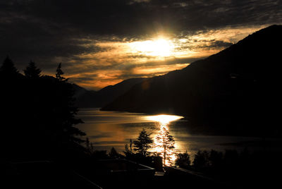 Silhouette trees by lake against sky during sunset