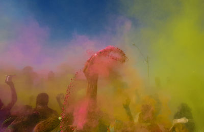 People playing holi against sky