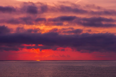 Scenic view of sea against dramatic sky during sunset