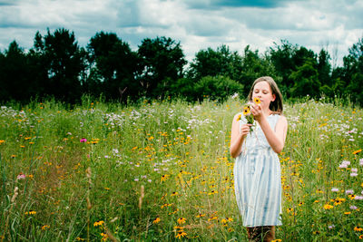 Beautiful young woman standing by flower field