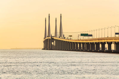 Bridge over sea against clear sky during sunset