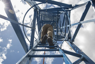 Worker climbing on construction crane, view from below