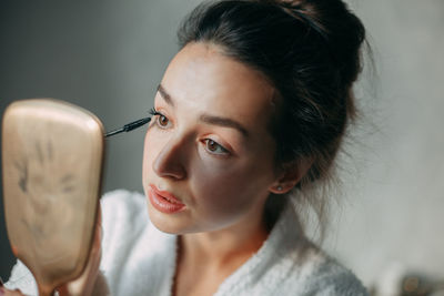 Brunette woman paints eyelashes with black mascara