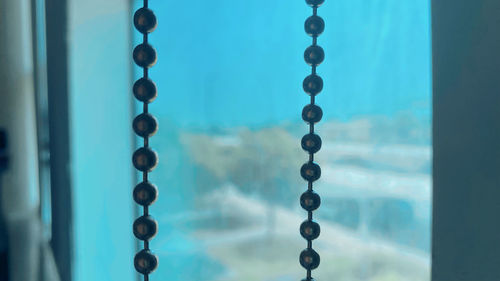 Close-up of chain hanging against window