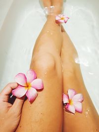 Low section of woman resting in bathtub at bathroom