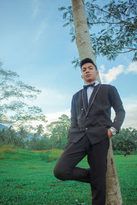 Young man standing on field against trees