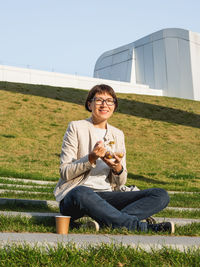 Portrait of young woman playing guitar while sitting on field