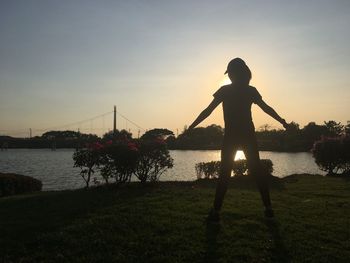 Silhouette man standing at beach against sky during sunset