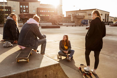 Friends talking while hanging out at skateboard park in city during sunny day