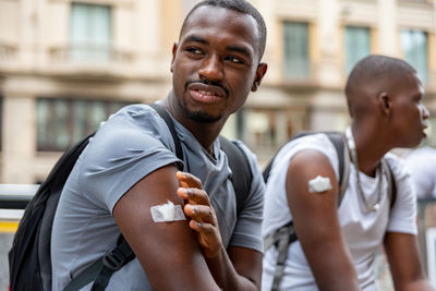 Afro men friends vaccinated showing his arm