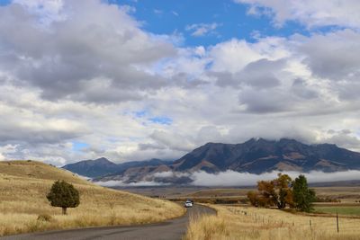 Road leading towards mountains against sky