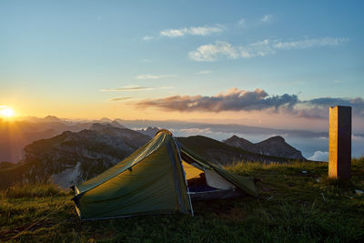 Tent on field against sky during sunset