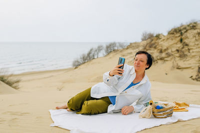 Adult woman on the beach in spring, summer orders online products for a picnic. purchase. fast