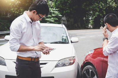 Young man standing on car in city