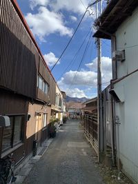 Empty road amidst buildings against sky