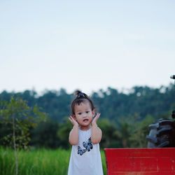 Girl standing on field against sky