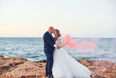 Couple kissing on beach against sea against sky