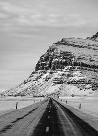 Empty road by mountain against sky