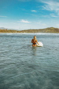 Rear view of woman in boat in sea against sky