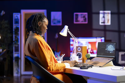 Side view of young woman using laptop while sitting at home