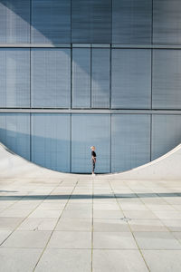 Rear view of man walking on modern glass building