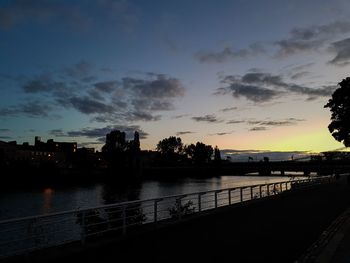 Silhouette bridge over river against sky during sunset