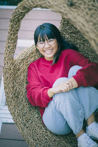 Asian teenager toothy smiling with happiness face ,relaxing on bamboo cradle.