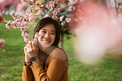 Portrait of young woman standing against plants