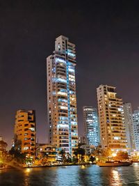 Illuminated buildings against sky at night