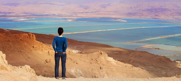 Full length rear view of woman standing at dead sea