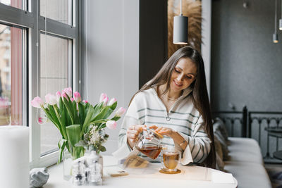 Portrait of young woman sitting on table at home