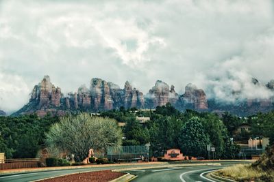 View of trees and buildings against cloudy sky