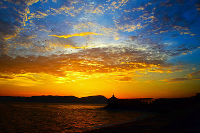 Scenic view of sea against dramatic sky during sunset