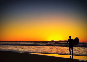 Silhouette of people on beach at sunset