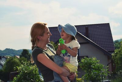 Cheerful mother and daughter against sky