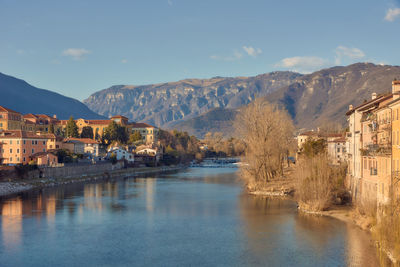 Buildings by river against sky