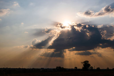 Low angle view of sunlight streaming through clouds