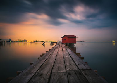Empty wooden pier over lake against sky during sunset