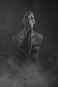 Portrait of naked female model practicing yoga against black background