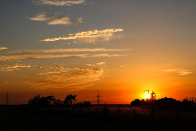 Silhouette trees on field against romantic sky at sunset