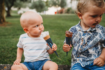 Young white toddler and baby eating ice cream in the summer