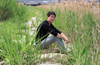 Young man looking away while sitting on land