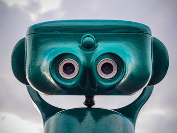 Close-up of coin-operated binoculars against cloudy sky