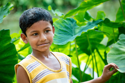 The portrait of a beautiful serene indian child in the background of a dark green forest